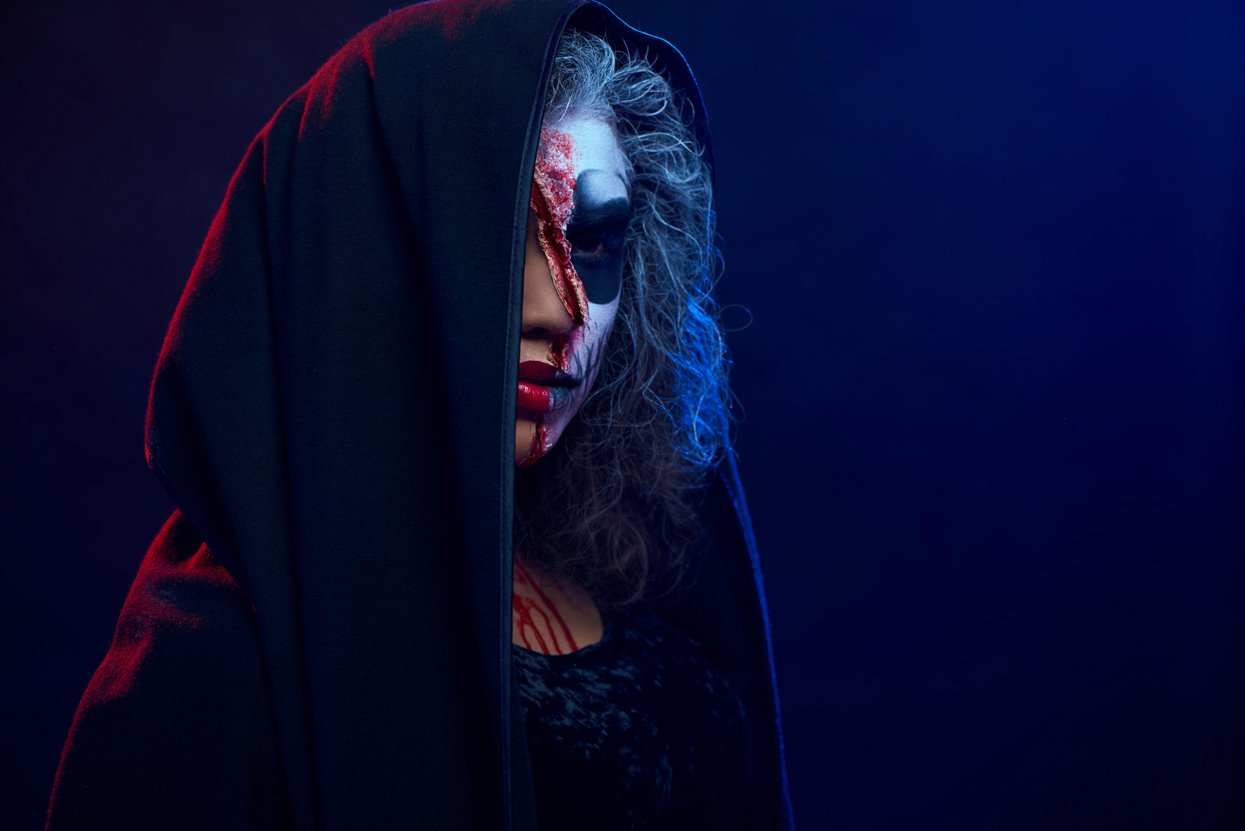 Side view of young girl with skull makeup in black mantle